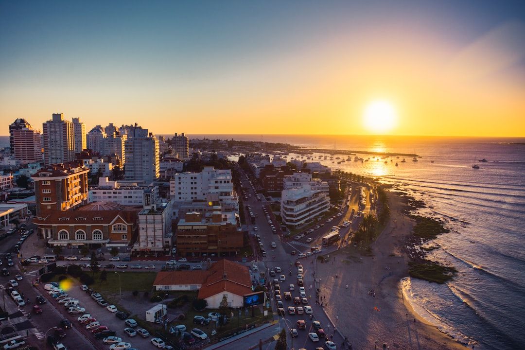 the sun is setting over a city by the ocean